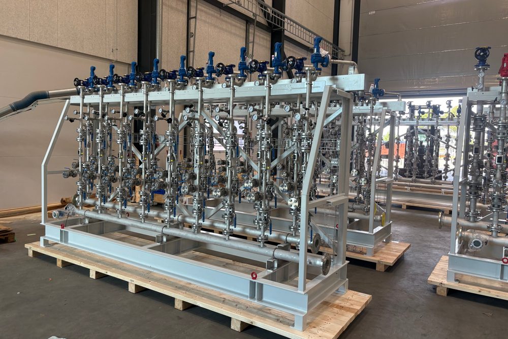Prefabricated stainless steel manifolds with valves and gauges on a steel frame in a workshop